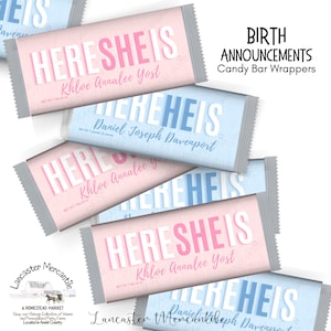 May include: Rectangular candy bar wrappers featuring the text HERE SHE IS in pink or HERE HE IS in blue. Each wrapper includes a personalized name in script font and the text NET WT 7 pounds 15 ounces. The wrappers have serrated silver edges.