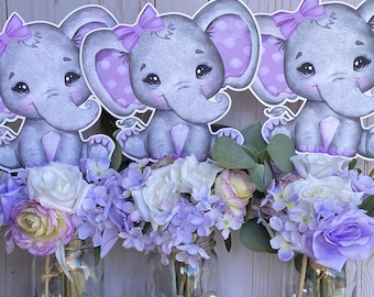 May include: Three mason jars filled with purple flowers and white pearls, each topped with a gray elephant cutout with purple polka dots and a purple bow.