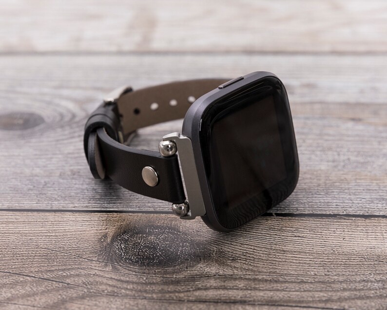 May include: A black leather watch band with a silver buckle and a black smartwatch with a touch screen.