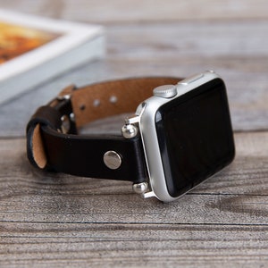 May include: A black leather watch band with silver accents and a silver Apple Watch.