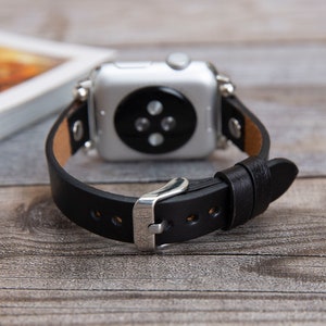 May include: A black leather watch band with a silver buckle and a silver Apple Watch face.