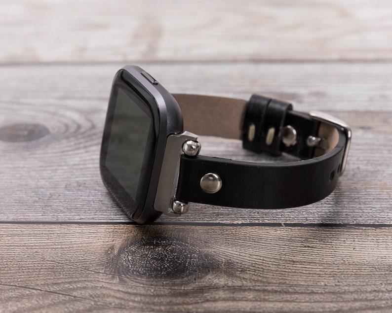 May include: A black leather watch band with silver accents and a black square watch face.