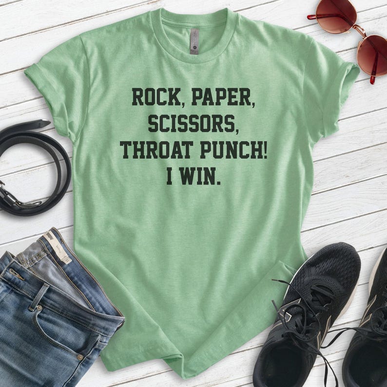 May include: A green t-shirt with the text "Rock, Paper, Scissors, Throat Punch! I Win."