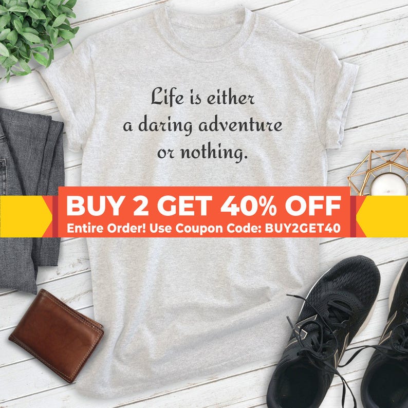 May include: A gray t-shirt with the text "Life is either a daring adventure or nothing."  The text is in black.  A red and yellow banner at the bottom of the image reads "BUY 2 GET 40% OFF Entire Order! Use Coupon Code: BUY2GET40".