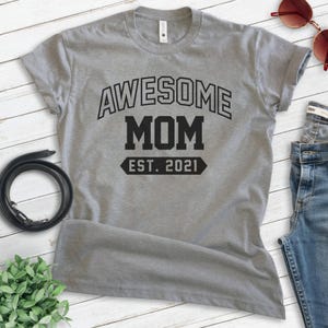 Peut inclure: T-shirt gris avec un texte noir qui dit "Awesome Mom Est. 2021".