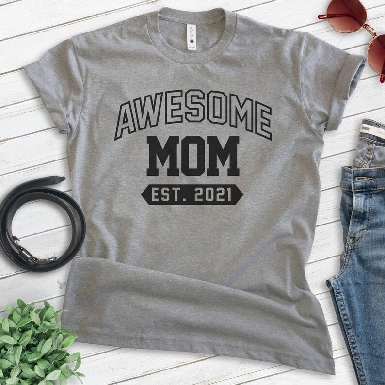 Peut inclure: T-shirt gris avec un texte noir qui dit "Awesome Mom Est. 2021".