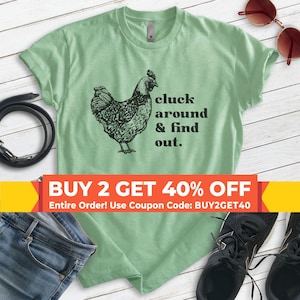 Może przedstawiać: Jasnozielona koszulka z czarną ilustracją kurczaka i napisem "cluck around & find out." Na zdjęciu widoczne są r&oacute;wnież okulary przeciwsłoneczne, pasek, dżinsy i trampki.