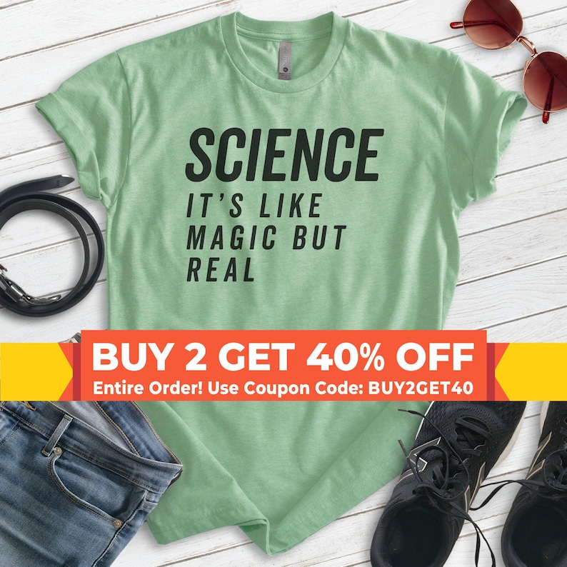May include: A green t-shirt with the text "SCIENCE IT'S LIKE MAGIC BUT REAL" in black. The text is centred on the shirt. There is a sale banner at the bottom of the image that says "BUY 2 GET 40% OFF Entire Order! Use Coupon Code: BUY2GET40"