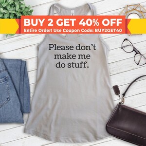 May include: A gray tank top with the text "Please don't make me do stuff." printed in black. The tank top is on a white wooden background with a pair of glasses and a purse.