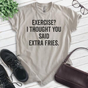 May include: A light gray t-shirt with the text "EXERCISE? I THOUGHT YOU SAID EXTRA FRIES." printed in black.