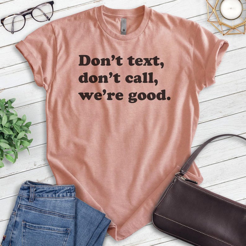 May include: A light pink t-shirt with the text "Don't text, don't call, we're good." printed in black.