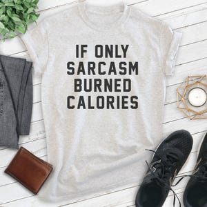 Puede incluir: Una camiseta gris con el texto "Si solo el sarcasmo quemara calor&iacute;as" impreso en negro.