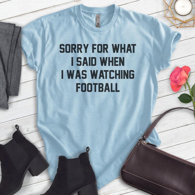 Pode incluir: Camiseta azul claro com o texto "Desculpe pelo que eu disse quando estava assistindo futebol".