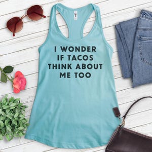 Może przedstawiać: Jasno błękitny top na ramiączkach z nadrukiem "I wonder if tacos think about me too" w kolorze czarnym.