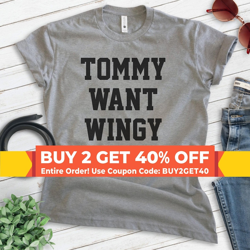 May include: A heather gray t-shirt with the words "TOMMY WANT WINGY" printed in bold black letters. The shirt has a crew neck and short sleeves. A banner at the bottom reads "BUY 2 GET 40% OFF".