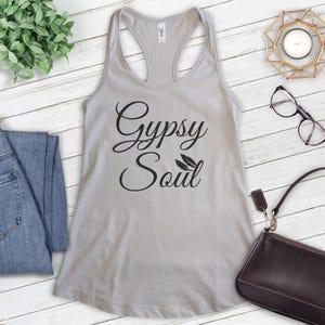 Może przedstawiać: Szary top na ramiączkach z napisem "Gypsy Soul" w czarnym, ozdobnym pismem. Dwa małe czarne pi&oacute;rka znajdują się nad słowem "Soul".