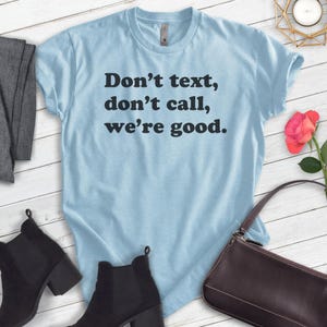 May include: A light blue t-shirt with the text "Don't text, don't call, we're good." printed in black.