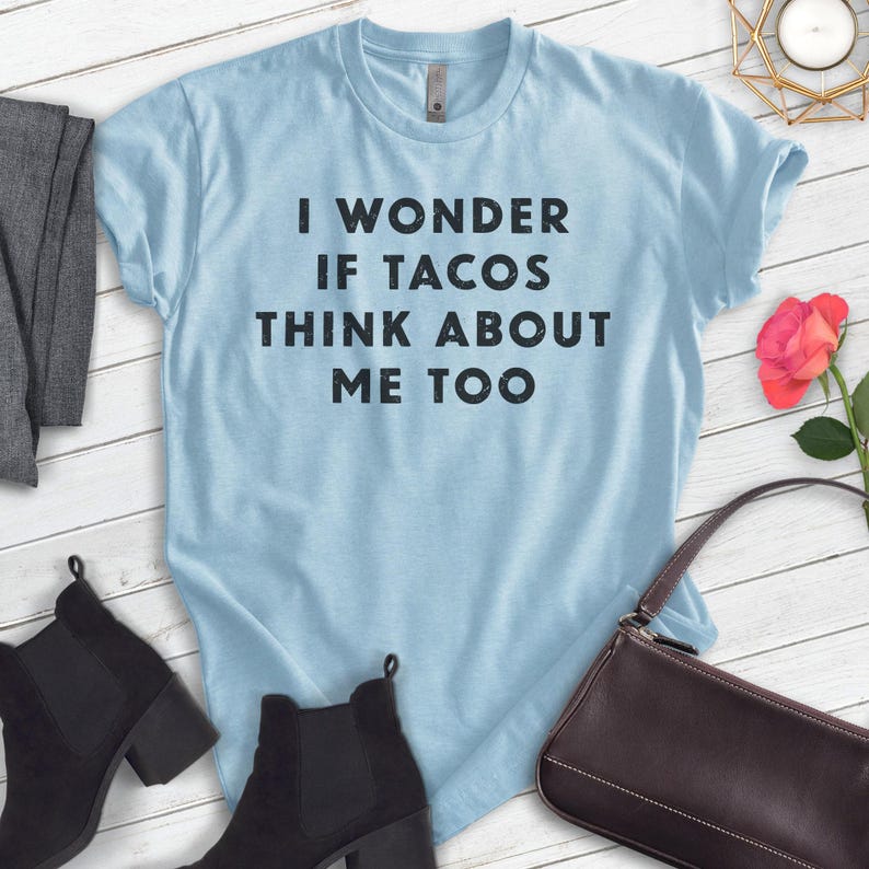 Puede incluir: Camiseta azul claro con el texto "I wonder if tacos think about me too" impreso en negro.