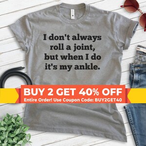 May include: Gray t-shirt with a funny saying: "I don't always roll a joint, but when I do it's my ankle."  The text is in black.  There is a yellow banner at the bottom that says "BUY 2 GET 40% OFF Entire Order! Use Coupon Code: BUY2GET40"