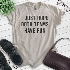 May include: A light gray t-shirt with the text "I just hope both teams have fun" printed in black.