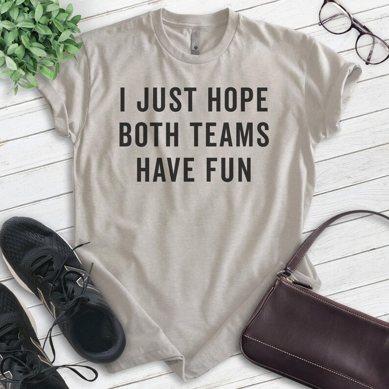 May include: A light gray t-shirt with the text "I just hope both teams have fun" printed in black.