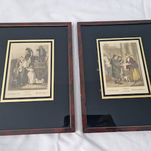 May include: Two framed black and white prints of historical scenes from London, England. The prints are in ornate gold frames with a dark brown mount.