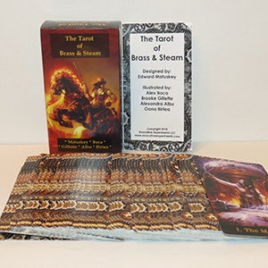 May include: A tarot deck box with the title "The Tarot of Brass & Steam" and a card from the deck showing a steampunk-inspired illustration of a magician. The box is red with gold accents and the card is purple with gold accents.