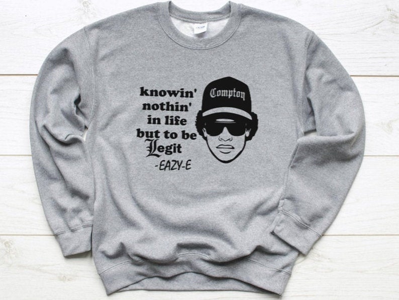 May include: Grey sweatshirt with a black print of a man wearing a hat that says "Compton" and the text "knowin' nothin' in life but to be Legit -Eazy-E"