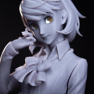 May include: A light gray anime-style character figure with short hair, wearing a collared shirt with a bow tie. The figure has detailed golden eyes and a smooth, matte finish. Text in the image includes KURU FIGURE, DEC 2025, and PATREON | KuruFigure.