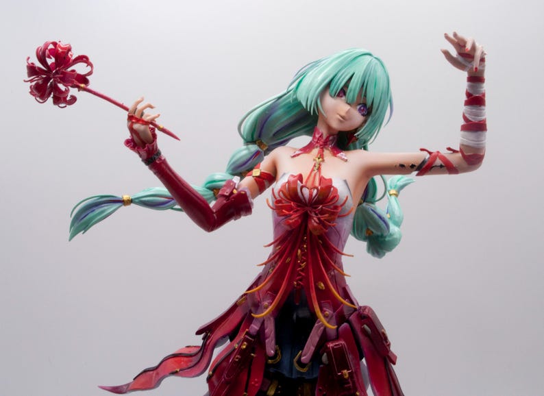 Puede incluir: Figura detallada de un personaje de anime femenino con cabello verde menta y un vestido rojo y blanco. La figura sostiene un objeto rojo en forma de flor y tiene cubiertas rojas para los brazos.