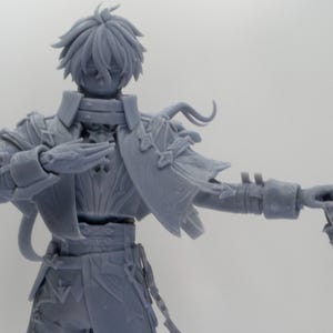 May include: A gray figurine of a character with detailed armor, a flowing cape, and stylized hair. The figure holds a decorative staff in one hand and has a hand raised in a gesture. The figurine is a fantasy-themed collectible.