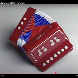 May include: A red toy accordion with white, blue, and red bellows. The accordion has white buttons and a decorative panel with white shapes. The word "Skyfling" is printed on the front.