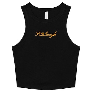May include: A black sleeveless crop top featuring a high neckline and a racerback style cut. The word Pittsburgh is embroidered in a gold-colored cursive script across the center of the chest area, positioned below the collar.