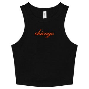 May include: Black crop top with a scoop neck and sleeveless design. The word "chicago" is written in orange cursive across the chest. The top is made of a soft, comfortable material.