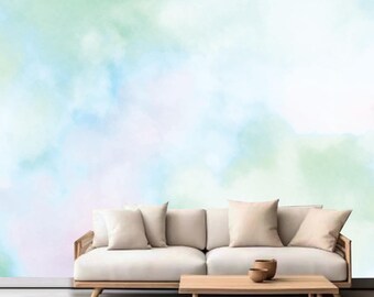 Könnte beinhalten: Ein weißes Sofa mit drei Kissen steht vor einer Wand mit einem Aquarell-Hintergrund in Blau, Grün und Weiß.