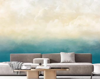 Könnte beinhalten: Ein graues Sofa mit einer weißen Wolldecke und einem weißen Kissen steht vor einer Wand mit einem Aquarellbild von Wolken und einem blauen Himmel.