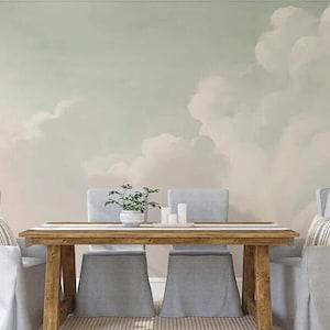May include: A dining room with a light green and white cloudy wall mural. A wooden table with four chairs is in the centre of the room. The chairs are upholstered in a light grey fabric. A small potted plant sits on the table.