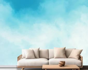 Könnte beinhalten: Ein weißes Sofa mit drei Kissen steht vor einer Wand mit einem blauen und weißen Aquarell-Himmelhintergrund.