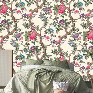 May include: A bedroom with a white floral wallpaper featuring pink, purple, and blue flowers. A green duvet cover is on the bed with a wicker basket at the foot of the bed.