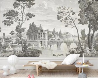 Puede incluir: Una ilustración en blanco y negro de un puente sobre un río en un entorno paisajístico. La ilustración presenta árboles, edificios y personas. La imagen está impresa en una pared, detrás de un sofá blanco con una manta blanca y una lámpara blanca.