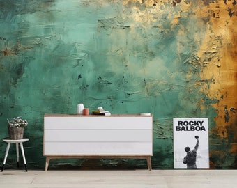 Könnte beinhalten: Eine weiße Kommode mit drei Schubladen steht vor einer grün-goldenen, strukturierten Wand. Links von der Kommode steht ein kleiner Topf mit einer Pflanze auf einem weißen Hocker. Rechts von der Kommode hängt ein Poster mit dem Text "ROCKY BALBOA" und einem Schwarzweißbild eines Mannes, der die Faust hebt.
