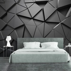 Può includere: Una camera da letto con un letto, due comodini e una carta da parati con motivi geometrici in bianco e nero. Il letto ha una testiera grigia e un copriletto bianco. I comodini sono in metallo e hanno un piano in vetro. La carta da parati è composta da forme geometriche.