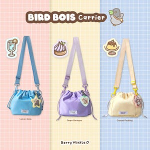 May include: Three drawstring crossbody bags in pastel colors: light blue, lavender, and cream. Each bag has a matching adjustable strap and a charm. The text "BIRD BOIS Carrier" and "Berry Winkle &" are displayed.