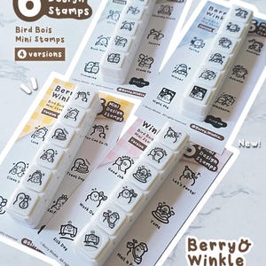 May include: A selection of white mini design stamps with bird-themed illustrations. Each set contains six stamps with different designs and phrases. The packaging includes the text "Bird Bois Mini Stamps" and "Berry & Winkle".