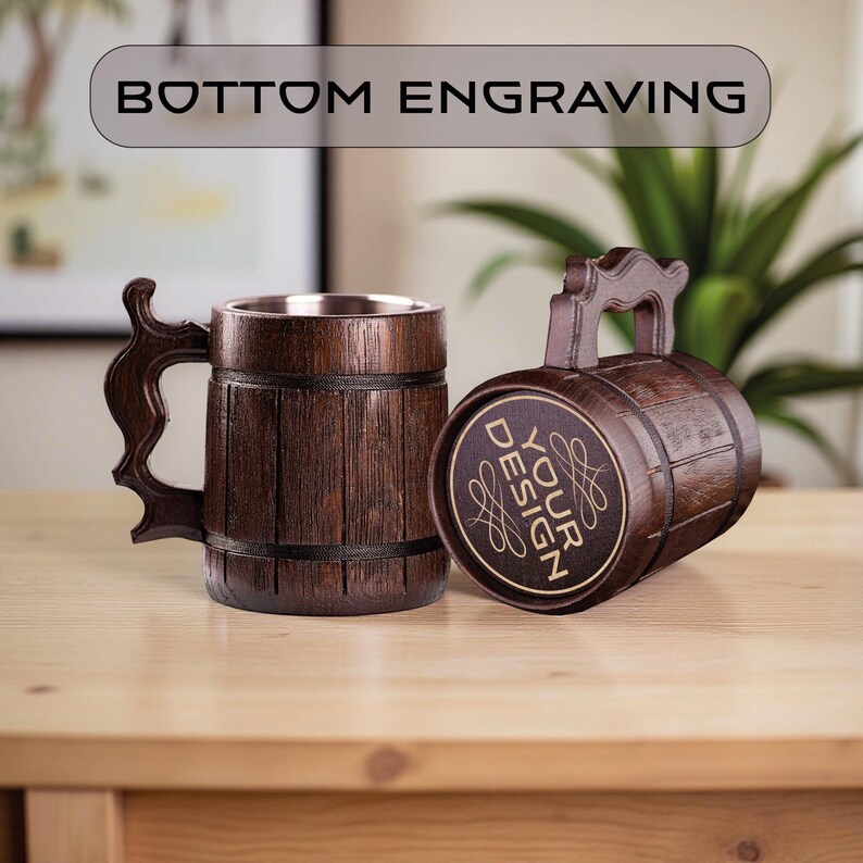 May include: Two wooden beer mugs with a barrel design. One mug is upright, the other is on its side. The mugs have a dark brown finish with a silver interior. The text "BOTTOM ENGRAVING" is above the mugs, and "YOUR DESIGN" is on the side of one mug.