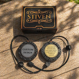 May include: A black and gold box with the name "STIVEN" and two custom design pendants with black cords. One pendant has "CUSTOM DESIGN" text, the other has space for custom text.