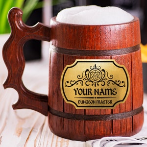 May include: A wooden beer mug filled with foamy liquid. The mug has a dark brown finish with a decorative gold plaque that reads "Your Name" and "Dungeon Master". The handle is intricately carved.