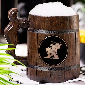 May include: A wooden beer mug filled with beer and foam. The mug has a dark brown finish with a decorative handle. A black circular emblem with a gold-colored graphic is on the front of the mug. The mug is sitting on a white surface.