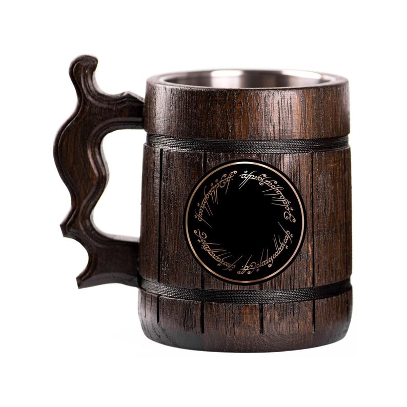 May include: A dark brown wooden beer mug with a decorative handle and a stainless steel interior. The mug features a black circular emblem with gold lettering. The mug is designed to resemble a wooden barrel.