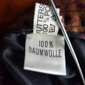 May include: White fabric label with black text that reads "FUTTERS 100% POLY 40" and "100% BAUMWOLLE".